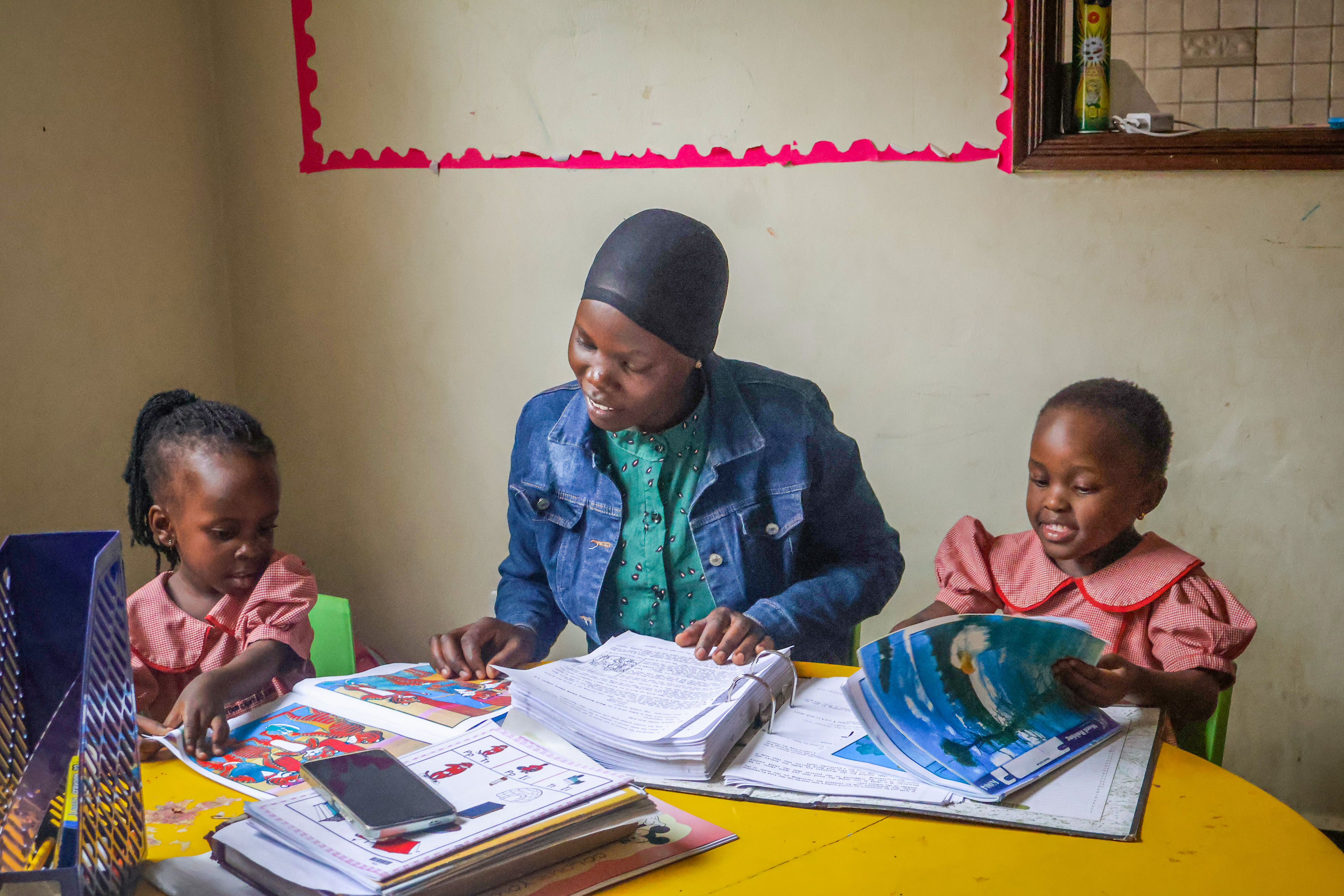 Teacher guiding two learners through their reading books